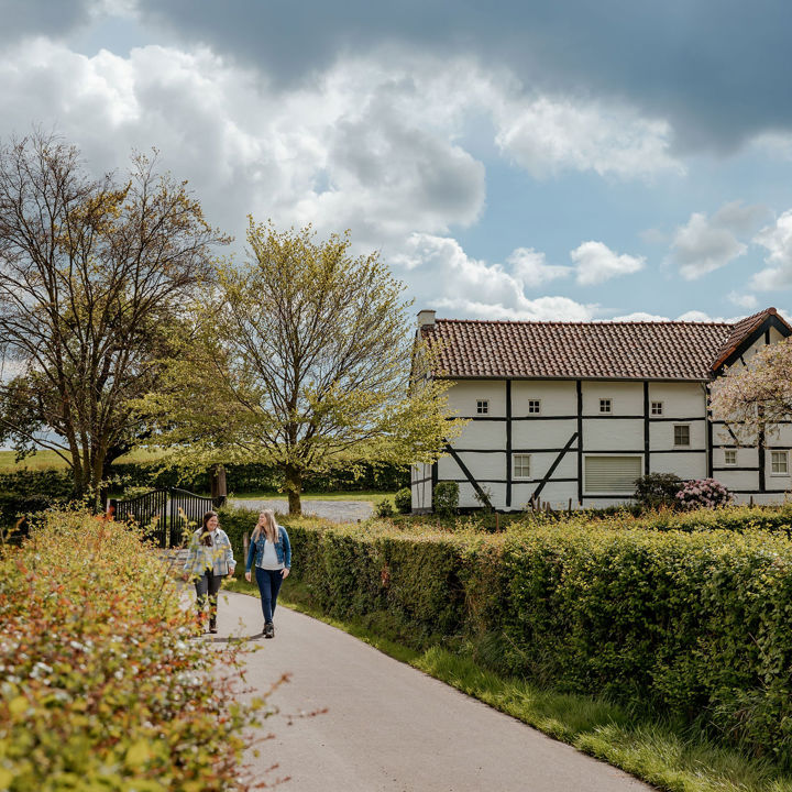 Twee dames wandelen voorbij een klassiek vakwerkhuisje in zuid-limburg.